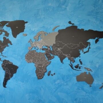 mapa mundi recortado com tons de cinza em um parede de concreto de tom azul