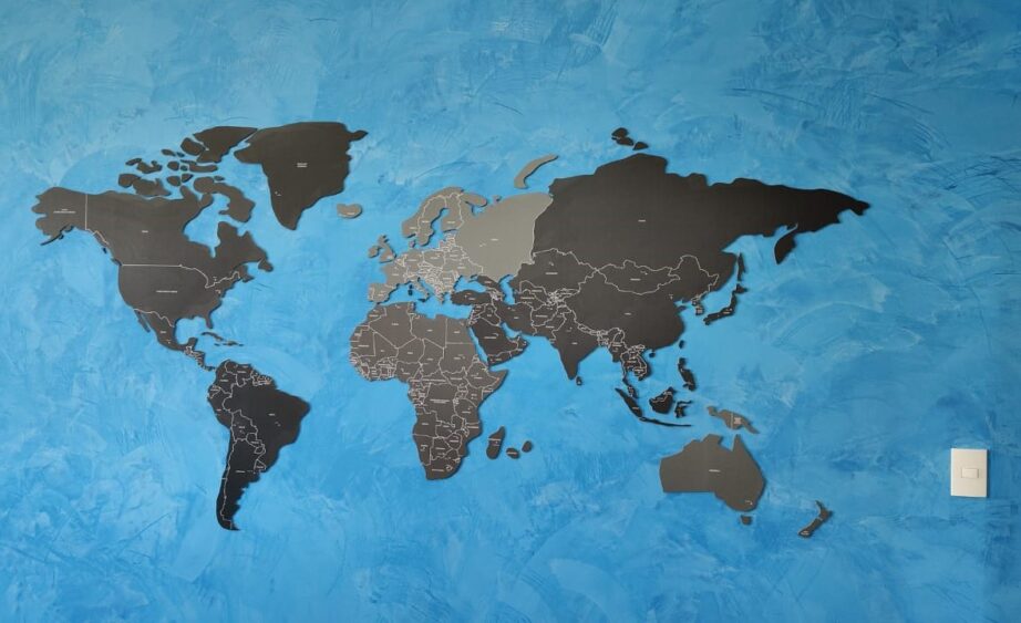 mapa mundi recortado com tons de cinza em um parede de concreto de tom azul